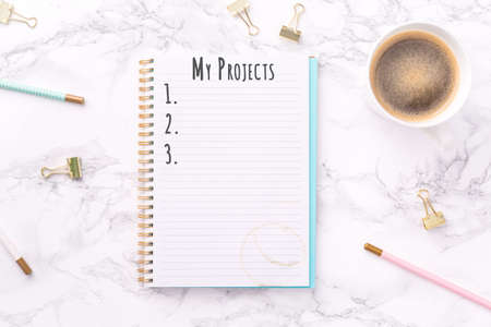 Festive golden stationary and coffee on white marble background. My Projects wording. Copy space. Top view. Horizontalの写真素材