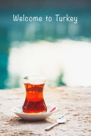 Hot turkish tea outdoors near water. Turkish tea and traditional turkish culture concept. Vertical. Toned image. Welcome to Turkey textの写真素材