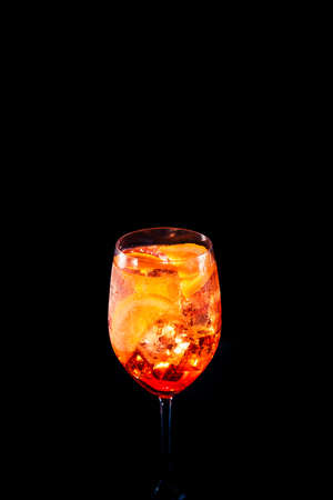 Stylish alcoholic trendy cocktail with orange slice on black background. Place for your text. Vertical photo.の写真素材