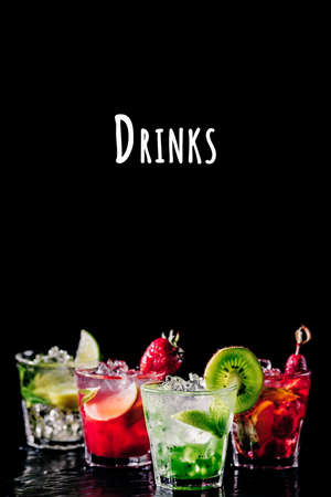 Four colorful tasty alcoholic cocktails in row at the bar stand. Luxury vacation concept. Place for text. Vertical, isolated on black. Drinks wordingの写真素材