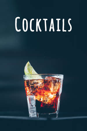 Cuba libre cocktail at the bar stand. Dark background. Vertical. Cocktails wordingの写真素材