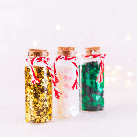 Glass bottles with glitter confetti on white background with bokeh lights. Holiday Christmas and New Year background. Squareの写真素材