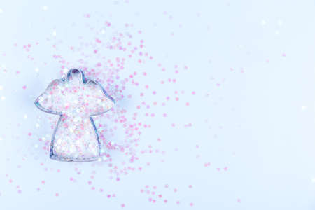 Flatlay with angel cookie cutter and snowflake sprinkles on blue background. Holiday, Christmas and New Year concept. Cozy homey details. Horizontalの写真素材