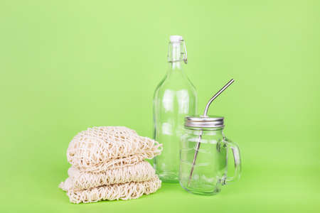 Reusable glass bottle and jar with metal straw and cotton bag on the light green drop, place for textの写真素材