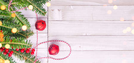 Red holiday bells with Christmas tree on rustic wooden background with ribbon and berries. Holiday season concept. Wide screen banner formatの写真素材