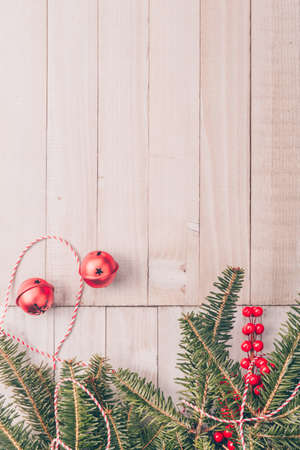 Red holiday bells with Christmas tree on rustic wooden background with ribbon and berries. Holiday season concept. Verticalの写真素材