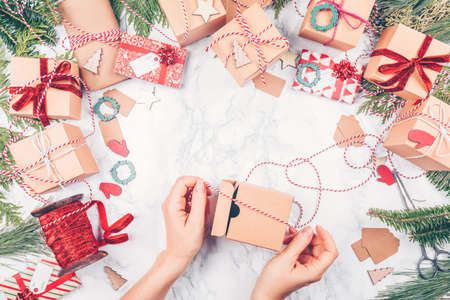 Craft boxes and wraps packed as Christmas gifts and red ribbons on white marble background. The woman packs Christmas gifts. Holiday season concept. Horizontalの写真素材