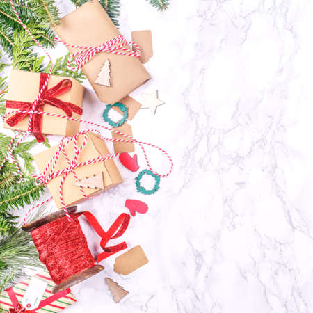 Craft boxes and wraps packed as Christmas gifts and red ribbons on white marble background. Holiday season concept. Square, place for textの写真素材