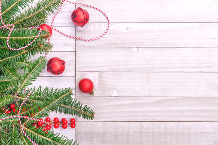 Red holiday bells with Christmas tree on rustic wooden background with ribbon and berries. Holiday season concept. Horizontalの写真素材