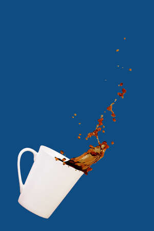 Levitating coffee mug with splashes. Coffee concept. Minimal art trend. Solid classic blue background. Verticalの写真素材