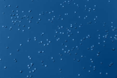 White and blue snowflakes sprinkles on blue. Festive holiday background. Celebration concept. Top view, flat lay. Horizontal.の写真素材