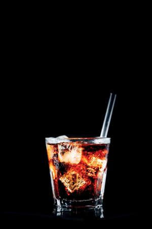 Cuba libre cocktail at the bar stand. Black background with place for text. Verticalの写真素材