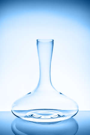 Luxury cristal decanter on the light background. Fine cristal glassware concept. Vertical toned in blueの写真素材