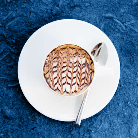 Overhead view of cafe latte with craft design on it toned in blue. Squareの写真素材