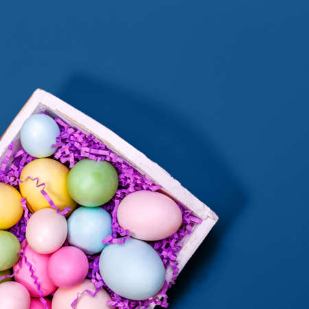 Multicolor eggs in a white tray. Creative Easter concept. Modern solid classic blue background. Squareの写真素材