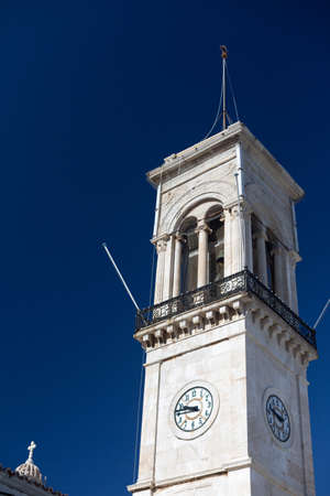 Bell tower with clock in Hydra Island, Greece on sunne day with clear classic blue sky . Verticalの写真素材
