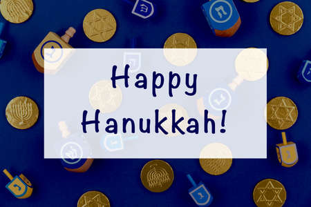 Dark blue background with multicolor dreidels and chocolate coins and Happy Hanukkah wording. Hanukkah and judaic holiday concept. Horizontalの写真素材