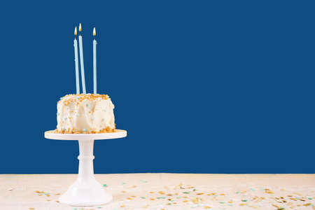 Birthday cake with candles on classic blue. Birthday party celebration concept. Horizontal, bold solid backgroundの写真素材
