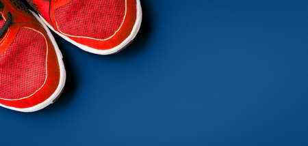 Sneakers on the solid classic blue backdrop. Keep fit athletic and healthy sports concept. Banner format, top viewの写真素材
