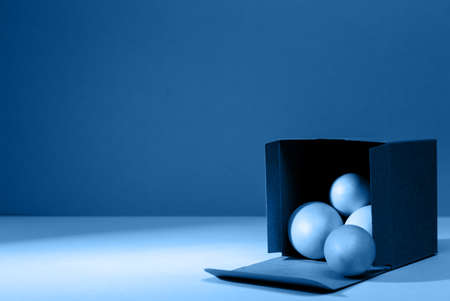 Eggs falling out of the craft cardboard box. Creative Easter concept. Modern solid classic blue background. Horizontal, cold tonedの写真素材