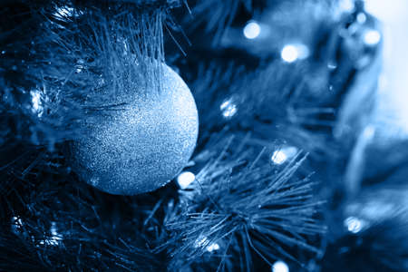 Seasonal background with Christmas toy on the tree toned in classic blue. Celebration concept. Soft focus. Horizontalの写真素材