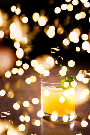 Screw driver cocktail with fresh mint on the dark background. Shallow DOF with festive bokeh lightsの写真素材