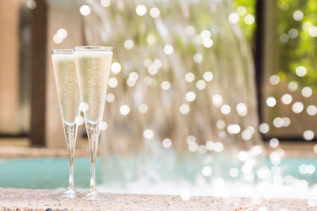 Two glasses of champagne near outdoor tub. Romantic getaway. Valentines background. Horizontal, shallow background with gentle festive holiday bokehの写真素材