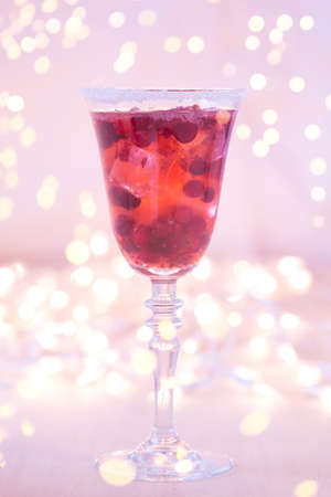 Glass of champagne and cranberry cocktail, macro. Lightweight background. Christmas mood. Vintage style. Shifted white balance, warm lilac tone. Vertical with gentle festive holiday bokehの写真素材