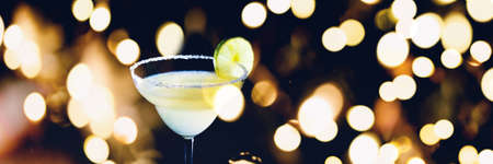 Classic daiquiri on the dark background. Luxury craft drink concept. Horizontal, banner format with festive holiday bokehの写真素材