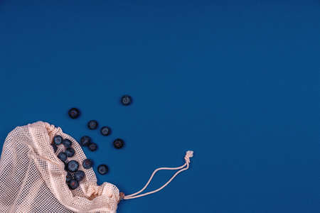 Mesh cotton reusable bag with blueberries on classic blue. Eco friendly shopping conceptの写真素材