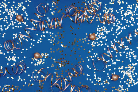 Holiday background with confetti, golden snowflakes, balls and ribbons on classic blue. Seasonal Christmas celebration backdropの写真素材
