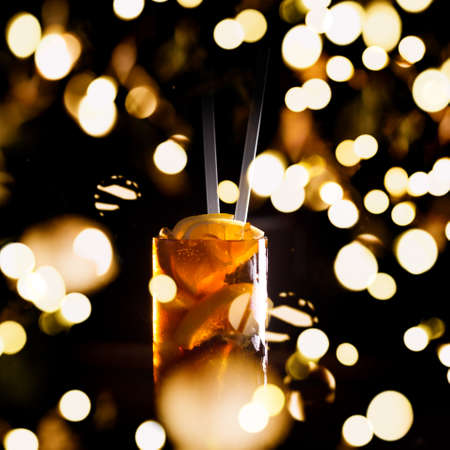 Cuba libre cocktail in a tall glass on the dark background. Shallow DOF with festive bokeh lightsの写真素材