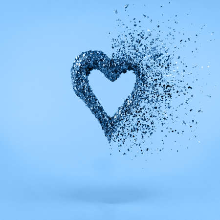 Glitter heart dissolving into pieces on classic blue background. Valentines day, broken heart and love emergence concept. Square.の写真素材