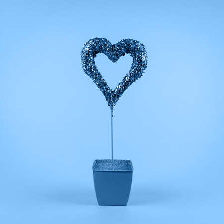 Glitter heart in flower pot on classic blue background. Valentines day and love growth concept. Square.の写真素材