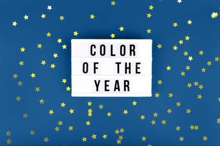Retro lightbox with Color of the year wording on the trendy solid blue backdrop, place for text with festive golden star shaped confettiの写真素材
