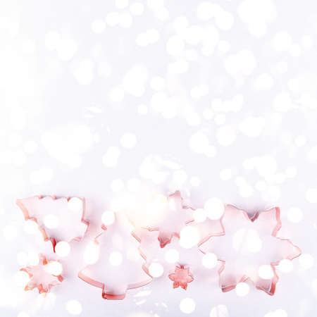 Flatlay with holiday tree and snowflake copper cookie cutters on white sparkling background. Holiday, Christmas and New Year concept Flat lay, top view background. Horizontal with festive bokeh lightsの写真素材