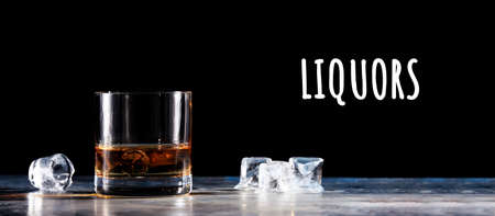 Glass of whiskey on the rocks with some ice on the table. Concept of hard liquor. Horizontal, wide screen banner format, isolated on black with Liquors wordingの写真素材
