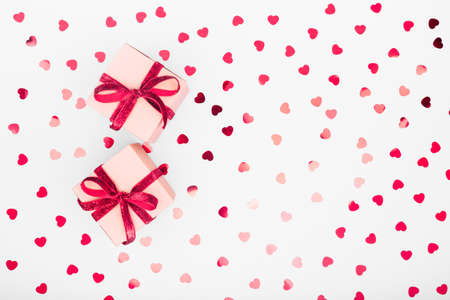 Craft box with red ribbon bow and glitter heart confetti. Valentine day and eco-friendly wrapping...