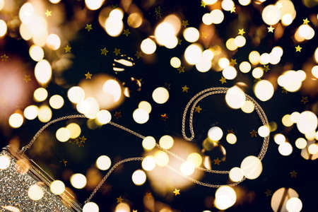 Festive evening golden clutch with star sprinkles on black. Holiday and celebration, Luxury accessories and party concept. Christmas and New Year Celebration. Horizontal with festive bokeh lightsの写真素材