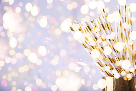 Gold and white paper straws in the golden glass. Christmas concept. Festive holiday party...