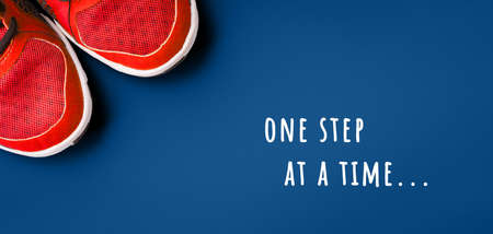 Sneakers on the solid classic blue backdrop with inspirational motivational quote Never give up. Keep fit athletic and healthy sports concept. Banner format, top viewの写真素材