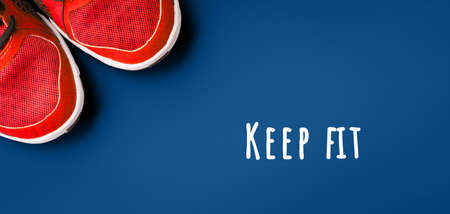 Sneakers on the solid classic blue backdrop with inspirational motivational quote Never give up. Keep fit athletic and healthy sports concept. Banner format, top viewの写真素材