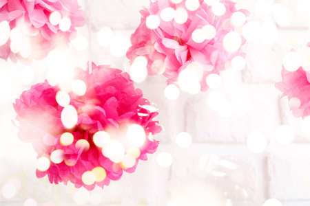 Paper flowers at the girl baby shower party. Baby shower celebration concept. Festive party background. Horizontal, white brick background with festive holiday bokehの写真素材