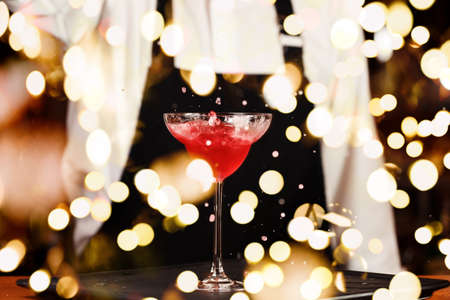 Barman in making cocktail at a nightclub. Nightlife concept. No face. Pouring into glass.. Horizontal with festive bokeh lightsの写真素材
