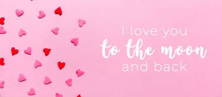 Love you to the moon and back wording and two tone heart sprinkles on the solid pink background. Romance, love, Valentines and mother's day concept. Flat lay, horizontal wide screen banner formatの写真素材