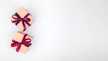 Craft boxes with dark red ribbon bows. Holiday, Christmas, New Year and Valentine day eco-friendly wrapping concept. Trendy minimalistic flat lay design background. Wide screen banner formatの写真素材