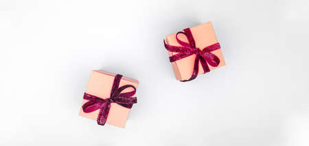 Craft boxes with dark red ribbon bows. Holiday, Christmas, New Year and Valentine day eco-friendly wrapping concept. Trendy minimalistic flat lay design background. Wide screen banner formatの写真素材