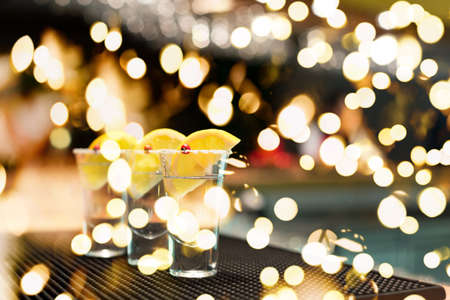 Three tequila shots with lemon on a bar ribber mat. Shallow DOF and toned with festive bokeh lightsの写真素材