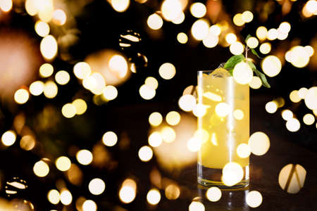 Screw driver cocktail with fresh mint on the dark background. Shallow DOF with festive bokeh lightsの写真素材