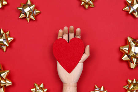 Futuristic image with a robot hand holding red heart on red drop with golden star bows. Robotic, ai, science, connection, technology, humanity conceptsの写真素材